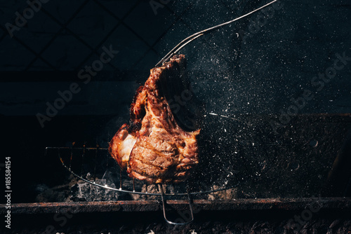 close-up view of delicious juicy meat with ribs and meat fork preparing on grill