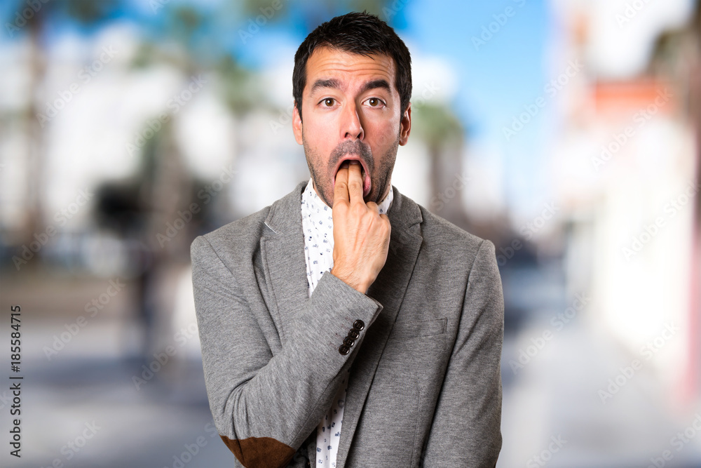 Naklejka premium Handsome man making vomiting gesture on unfocused background