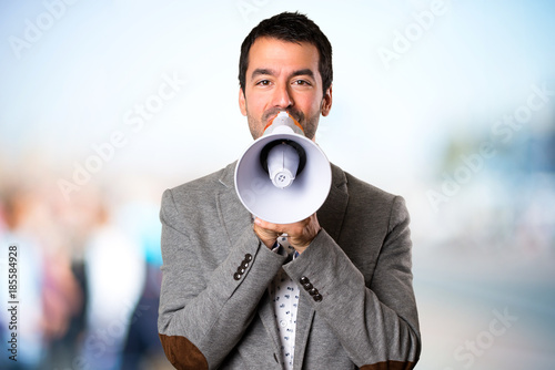 Handsome man holding a megaphone on unfocused background © luismolinero
