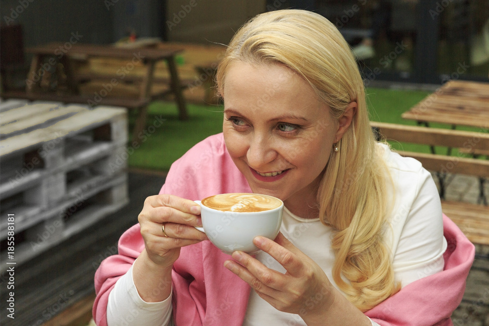 Smiling beautiful woman 45 years old drink coffee in a cafe. Smiling beautiful woman 45 years old drink coffee in a cafe.