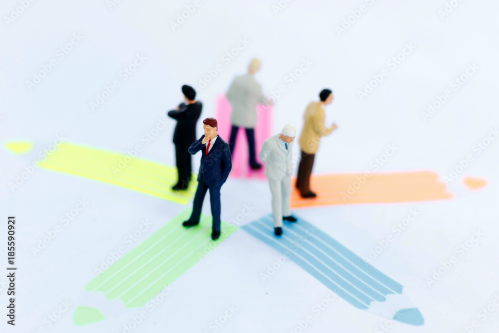 Miniature people: business team standing whit arrow pathway choice. Business decision concept. Miniature people: business team standing whit arrow pathway choice. Business decision concept.