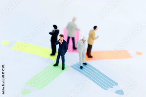 Miniature people: business team standing whit arrow pathway choice. Business decision concept.