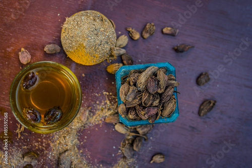 Close up of water of Black cardamom with its powder and raw whole black cardamom.