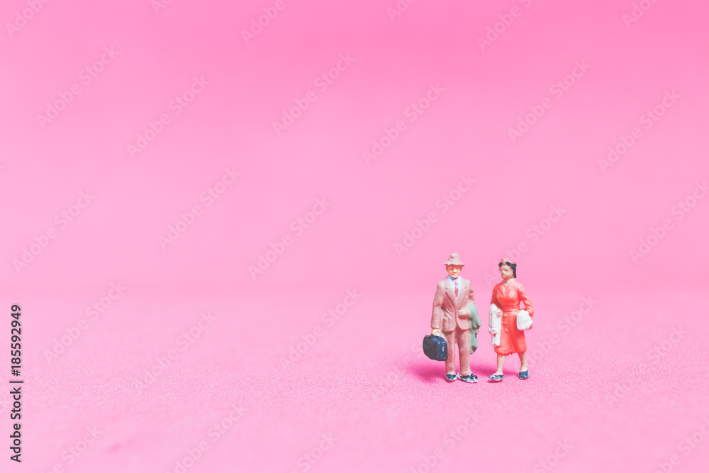Fototapeta premium Miniature people : Couple of travellers on pink background&nbsp;, Valentine's day concept