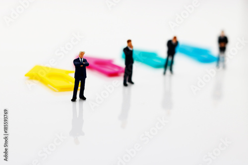 Miniature people standing with arrow pathway choice. Business decision concept.