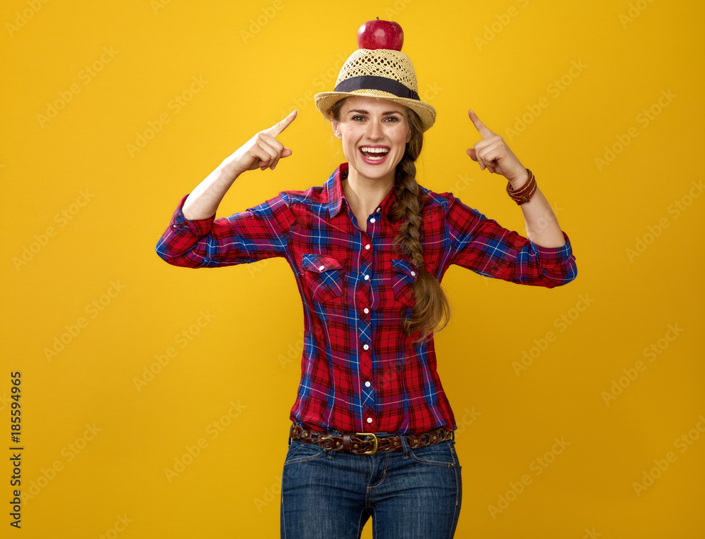 happy woman grower isolated on yellow pointing on apple on head