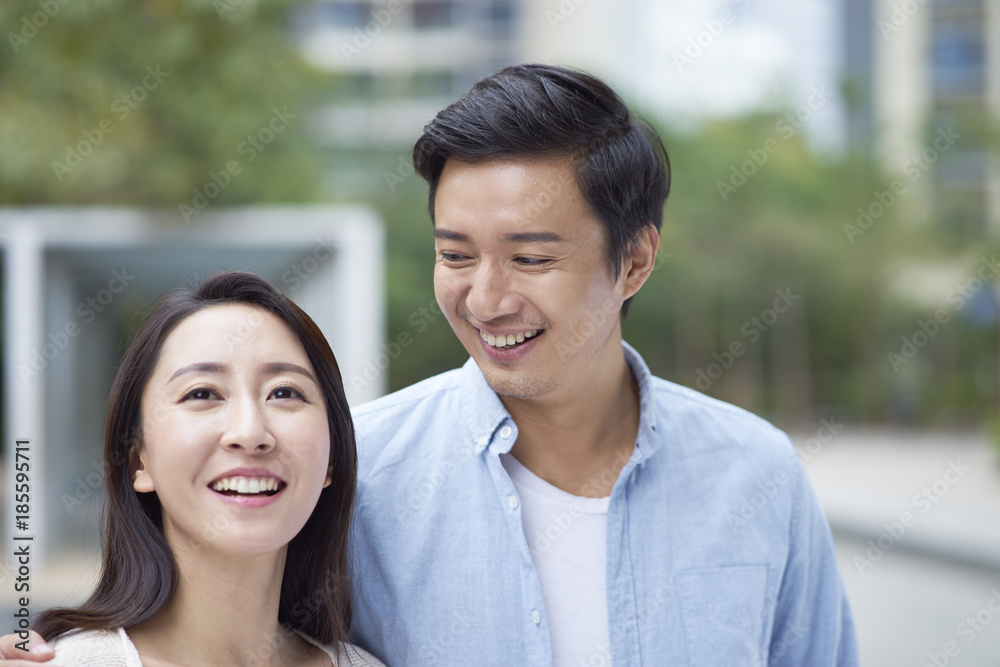 portrait of young Chinese couple standing & smiling outdoor