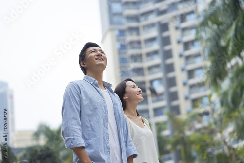 Photography portrait of young Chinese couple standing & smiling outdoor in garden