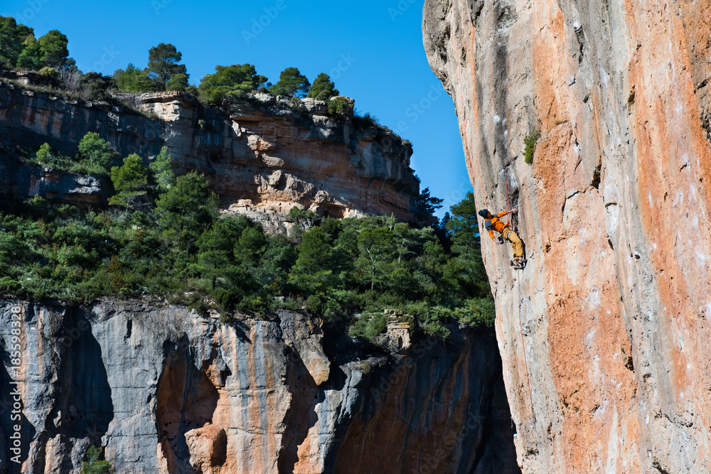Outdoor sport activity. Rock climber ascending a challenging cliff. Spain