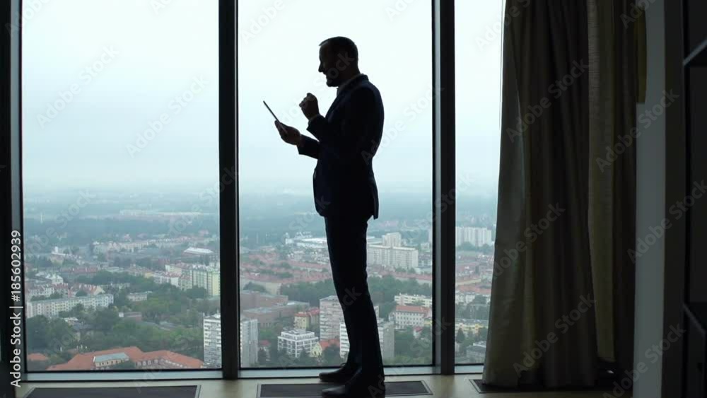 Happy businessman reading good news on tablet by window, super slow motion 240fps
Happy businessman reading good news on tablet by window, super slow motion 240fps