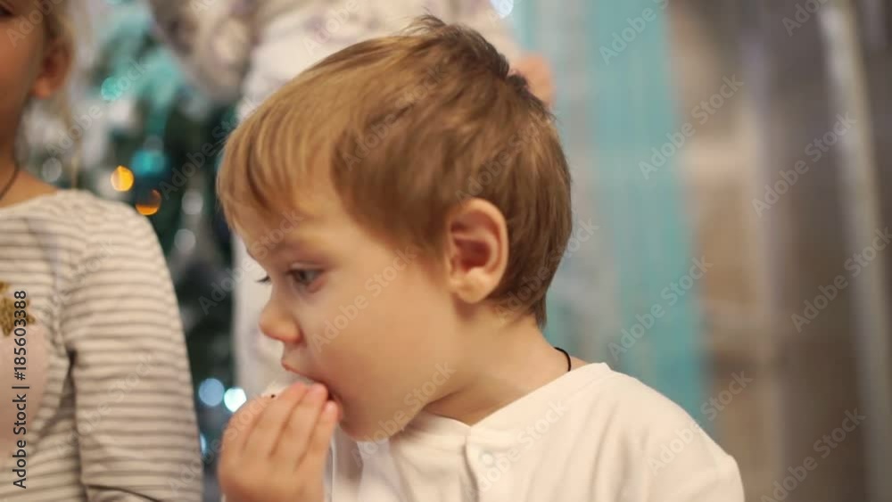 Happy children in pajamas eat gingerbread and have fun in the New Year's interior Happy children in pajamas eat gingerbread and have fun in the New Year's interior