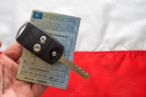 Dowód rejestracyjny i kluczyki do samochodu na tle flagi Polski.