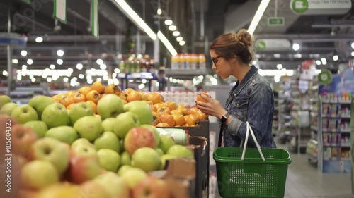 Young woman chooses fruit oranges in the store
