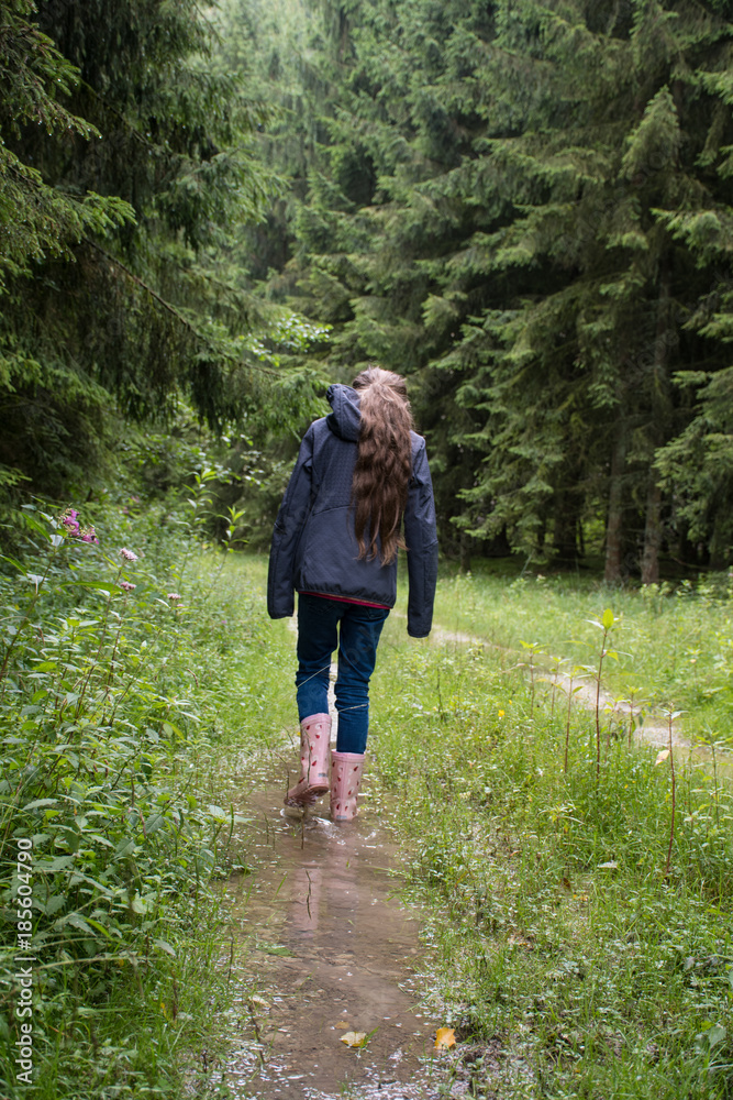 Mädchen geht im Wald durch Pfütze nach Regen