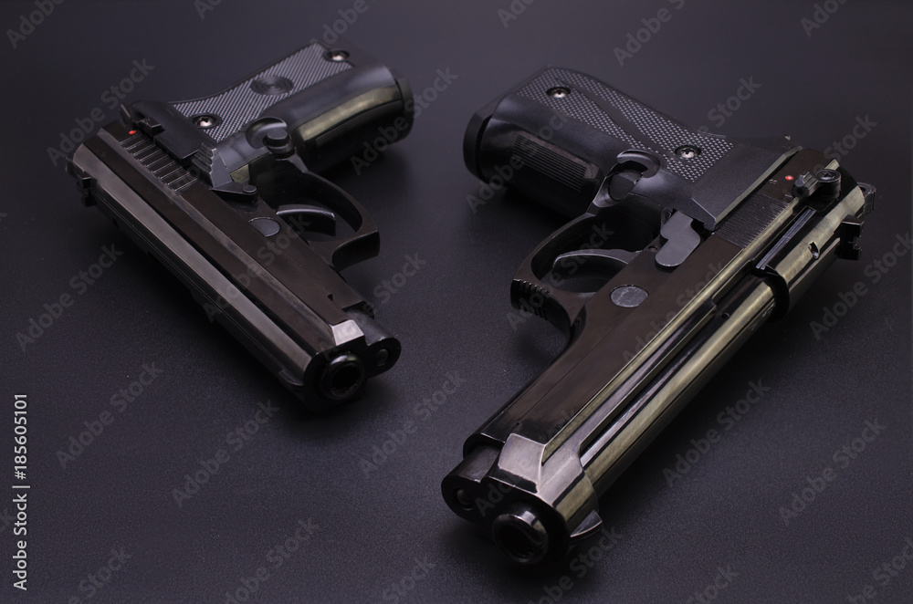 two black automatic pistols on a black background two black automatic pistols on a black background