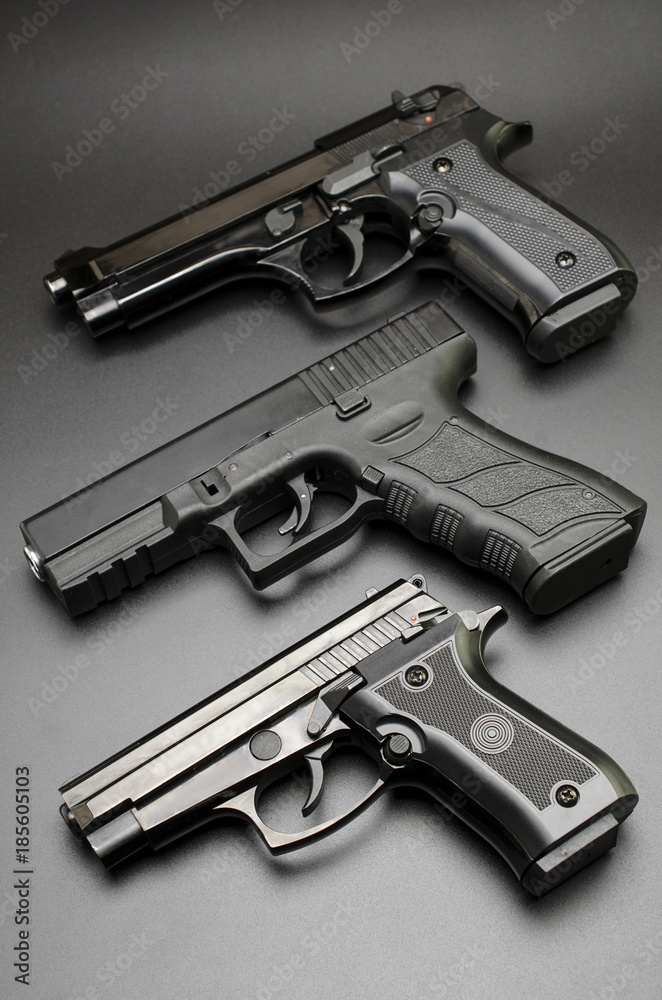 three black pistols on a black background. three black pistols on a black background.