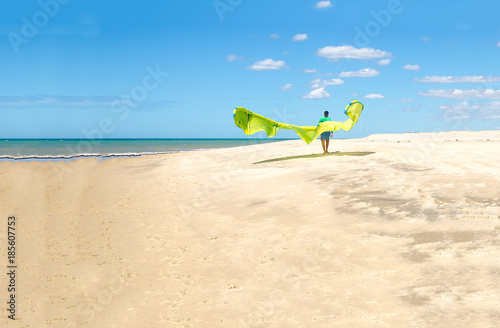 Young sportman carrying a kite surf in a beach