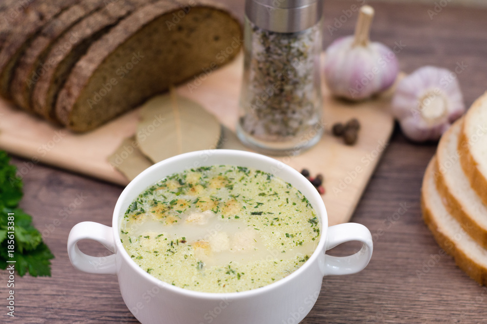 Mushroom soup with croutons in a white dish is on a wooden table. Mushroom soup with croutons in a white dish is on a wooden table.