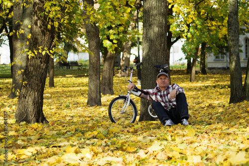 Senior and his bicycle in autumn park.