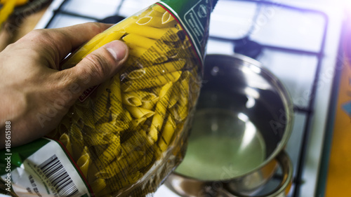 Man's hand with packing pasta at the pot with water concept cooking food