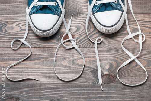 Sneakers similar to keds on a New Year rustic wooden background, Christmas gift to an athlete, white laces written 2018
 photo