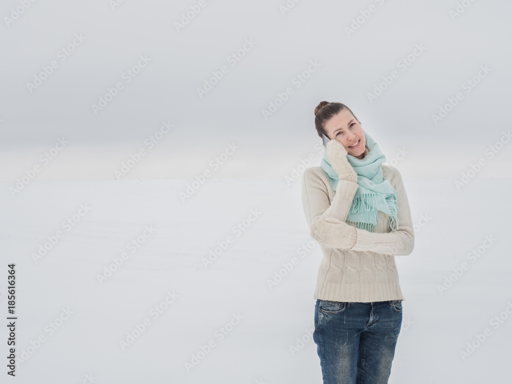 Beautiful and young woman holds in her hands a mobile phone in a snowy field Beautiful and young woman holds in her hands a mobile phone in a snowy field