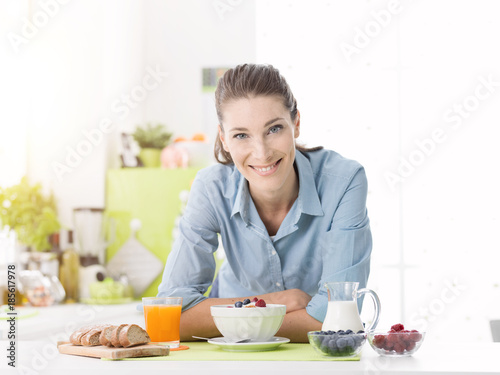 Smiling woman having breakfast at home
