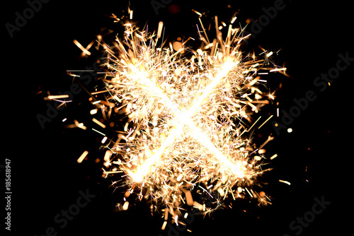 Letter "X" made of sparklers isolated background.