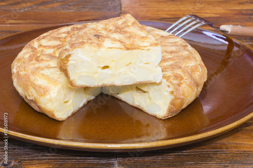 Tortilla española con patatas con un trozo cortado, sobre un plato de barro 