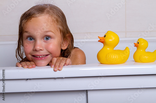 Fotografie baby girl taking bath with foam and toys