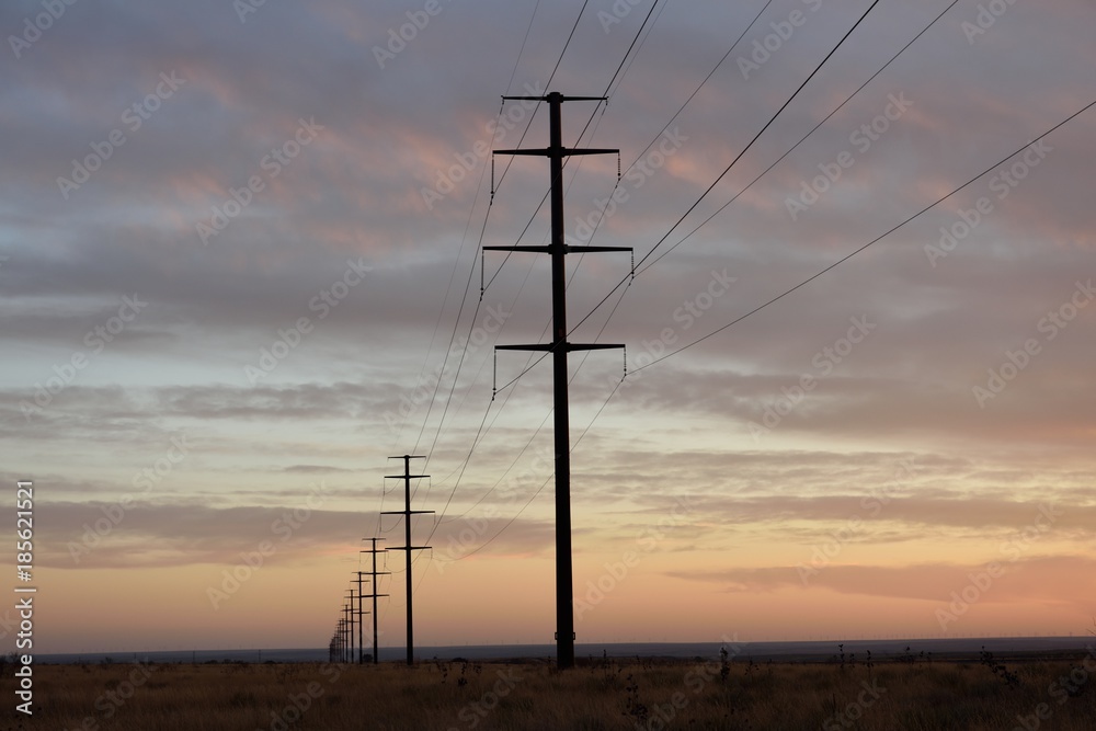Electrical grid infrastructure, row of overhead high voltage power lines crossing through an empty rural landscape in Texas / USA