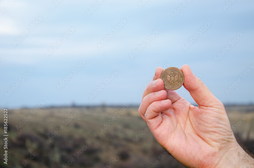 old coin in the man's hand against the sky old coin in the man's hand against the sky