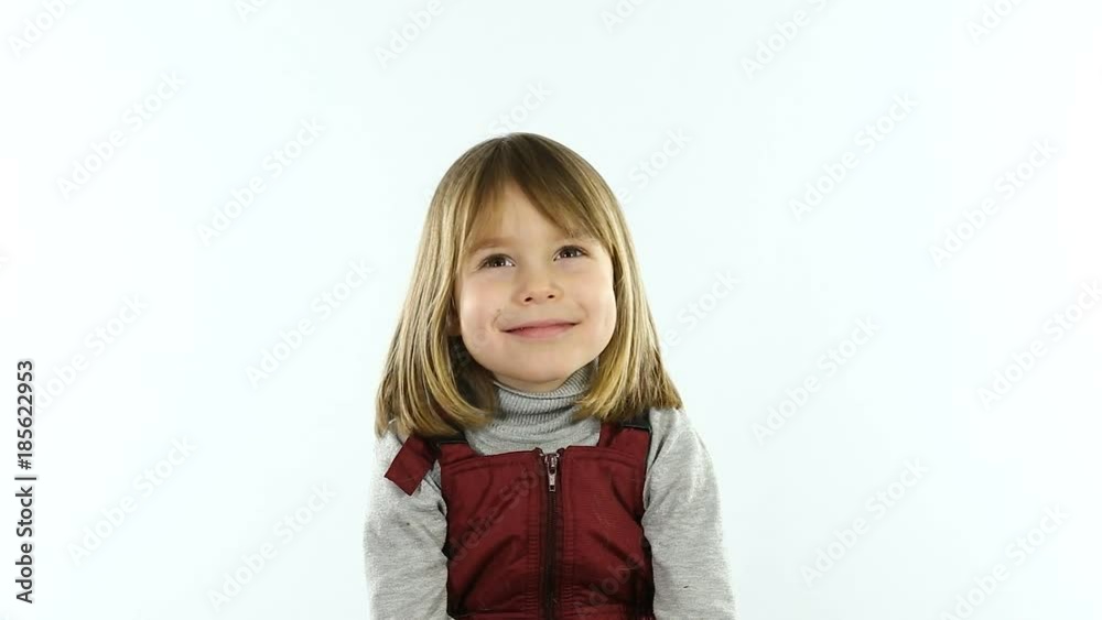 Studio, white background. A little girl of four - five years, with blond hair, posing on camera sitting on a chair. A child of European appearance. Studio, white background. A little girl of four - five years, with blond hair, posing on camera sitting on a chair. A child of European appearance.