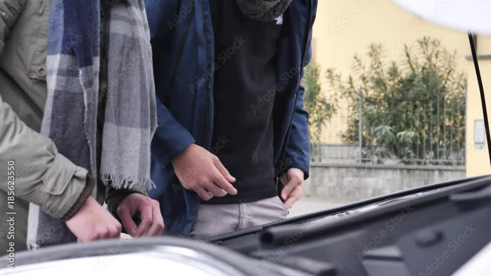 Young men looking up information while trying to repair car engine. Young men looking up information while trying to repair car engine.
