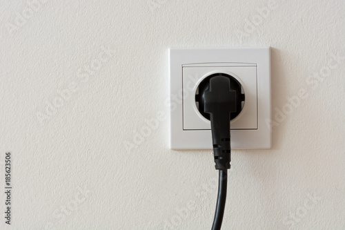 Black 220 volt power plug plugged in a socket
