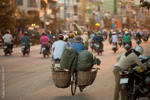 Tableau sur toile evening rush hour in Asian city, a lot of people on motorcycles are driving on t