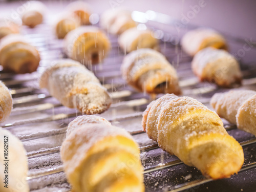 Freshly baked cookies with powdered sugar pouring over them from the sifter. photo