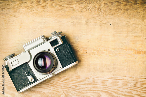 Old retro camera on vintage rustic wooden planks boards. Education photography courses back to  school concept abstract background. Close up, top view, copy space. Analog camera photo toned.