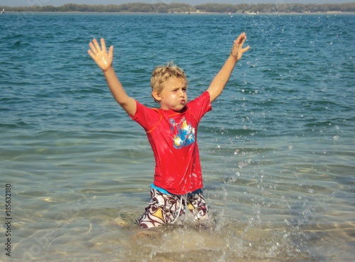 A boy is playing in shallow water, having fun splashing  photo