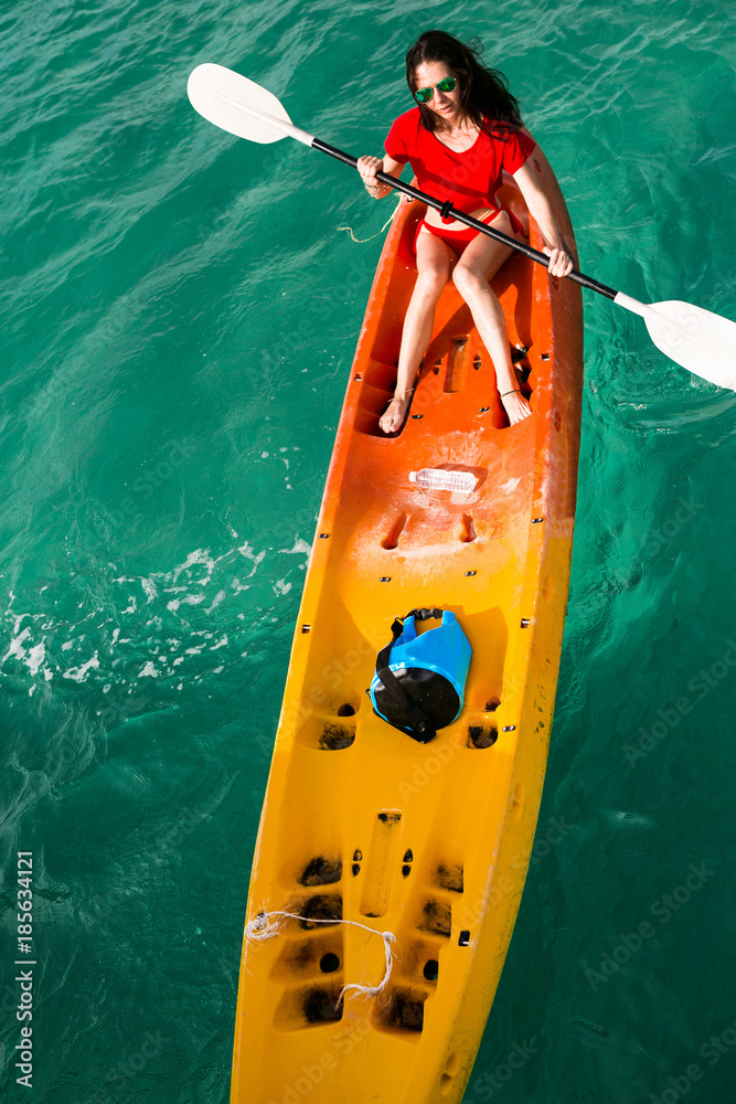young woman girl in red bikini paddling on red, orange, yellow