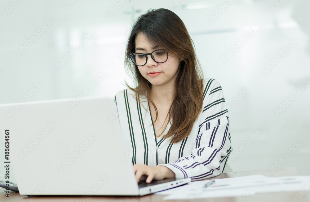 Young business woman working on laptop in office. Young business woman working on laptop in office.