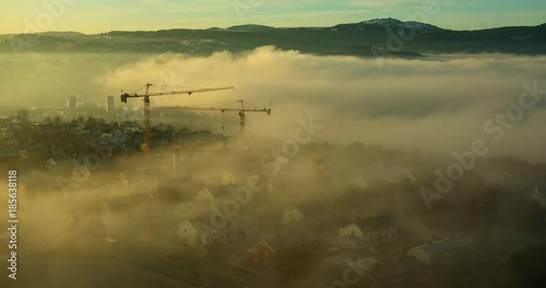 TRONDHEIM, NORWAY – FEBRUARY,2017 : Amazing timelapse of clouds moving over Trondheim cityscape at sunrise with cranes working and mountain in view photo