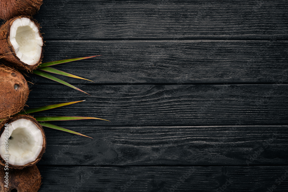 Coconut on a wooden background. Tropical fruits and nuts. Top view. Free space for text.