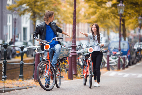 Photography Young happy caucasian couple on bikes in old streets in Amsterdam
