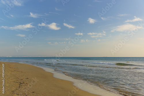 The sloping sandy beach of the sea. Calm. Clear sky, altocumulus clouds (lat. Altocumulus)