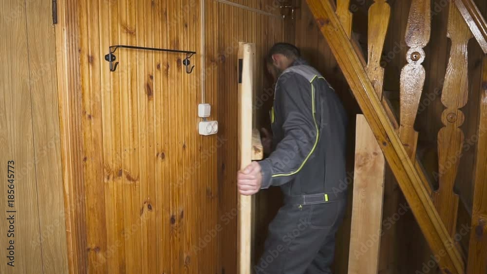 The worker sets up a self-made door in a wooden interior The worker sets up a self-made door in a wooden interior