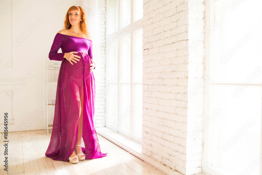 pregnant woman in purple dress in white room