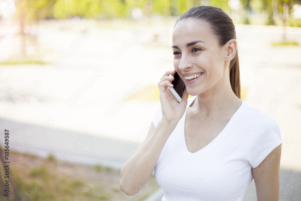 Attractive brunette woman talking on mobile phone with friend Attractive brunette woman talking on mobile phone with friend