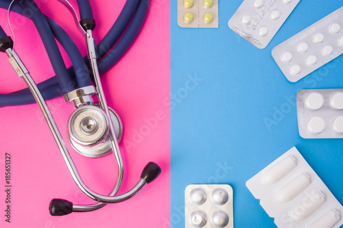 Pills, drugs, medictions and suppositories in blister package and medical stethoscope in two colors background: blue and pink. Concept of drug therapy, treatment, curing diseases of men and women photo