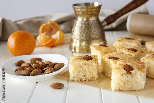 Still life Pieces Basbousa (namoora) traditional arabic semolina cake with almond nut and syrup, orange and cooper jezva. Copy space.